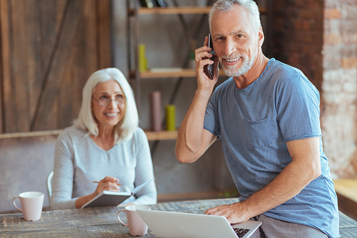 Woman writing in a journal and man using a computer while he's on the phone